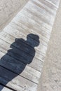 Shadow of a woman with hat, taking a selfie on a wooden pontoon at the beach Royalty Free Stock Photo