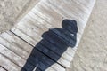 Shadow of a woman with hat, taking a selfie on a wooden pontoon at the beach Royalty Free Stock Photo