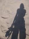 Shadow of Woman on Sand Holding Sandals in Hand Royalty Free Stock Photo