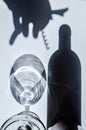 Shadows of a bottle of wine and glass, and shadow of hand and corkscrew on a white textured surface. Royalty Free Stock Photo