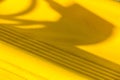 Shadows dance over vibrant yellow surface with intricate patterns captured in warm afternoon light Royalty Free Stock Photo