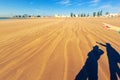 Shadows on the golden sand - two people take picture of Essaouira port