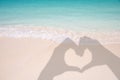 Shadows of hands forming a heart on sand and caribbean beach Royalty Free Stock Photo