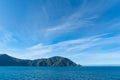 Shadows on hills under blue sky with light wispy cloud entering Queen Charlotte Sound