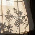 Shadows of leafy branches are cast on a light-colored fabric curtain, creating intricate patterns. Royalty Free Stock Photo