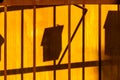 Shadows of mailboxes projecting on yellow wall behind rusty metal gate Royalty Free Stock Photo