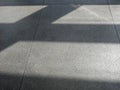 Shadows from morning sun on concrete airport waiting hall floor.