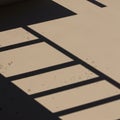 Shadows of parallel lines and rectangles fall on a textured beige surface. The Royalty Free Stock Photo