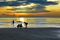 Shadows of people fishing on the beach at sunrise. Royalty Free Stock Photo