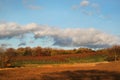 Fall landscape of hillside vineyard below a blue sky with clouds