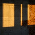 Shadows of rectangular windows fall on a concrete wall, next to a section of exposed red brickwork. Royalty Free Stock Photo