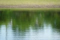 Shadows reflect of coast of green tree and grass.