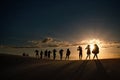 Shadows on the sandy beach and Silhouette of people`s group walking across the dunes during sunset Royalty Free Stock Photo