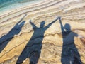 Shadows of three happy people at beach raising hands