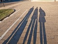 Shadows of three people in coats on cobble-stone pavement Royalty Free Stock Photo