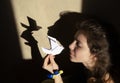 Shadows on wall from a paper dove of peace and a woman`s face. Stop the war in Ukraine