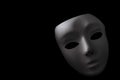 Shadowy disguise, secret society and creepy emotionless figure concept with a vintage white blank mask with dramatic light and Royalty Free Stock Photo