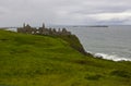 The shadowy ruins of the medieval Irish Dunluce Castle on the cliff top overlooking the Atlantic Ocean in Ireland