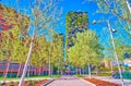 The shady alley of Biblioteca degli Alberi Park with bosco Verticale buildings on background, Milan, Italy