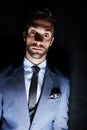 Shady business. Studio portrait of an eerie looking young man standing against a dark background.