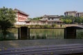 Shady fenced riverside with traditional buildings in background