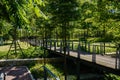 Shady planked footbridge in verdant city of sunny summer