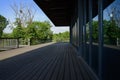 Shady planked veranda outside glass-walled building in sunny sum