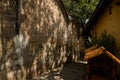 Shady stone-paved path between ancient wall and tile-roofed building in sunny afternoon,China
