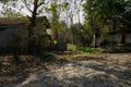 Shady unpaved country road before tile-roofed farmhouse in sunny