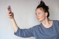 Shaggy sad woman holding smartphone in outstretched arm to keep distance and taking photo Royalty Free Stock Photo