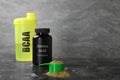 Shaker with abbreviation BCAA, Amino Acid complex in plastic jar and powder on table. Space for text