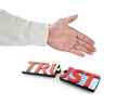 Shaking hand and puzzle pieces with word TRUST