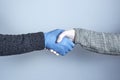 Shaking hands in medical gloves on a gray background. The concept of a safe handshake