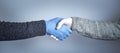 Shaking hands in medical gloves on a gray background. The concept of a safe handshake.