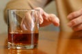 Shaking woman hand reaching of glass with whiskey standing on a wooden table, woman`s alcoholism problem
