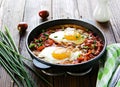 Shakshuka or fried eggs in tomato sauce with red bell pepper in a serving cast-iron frying pan on a wooden background Royalty Free Stock Photo