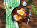 Shakshuka or fried eggs in tomato sauce with red bell pepper in a serving cast-iron frying pan on a wooden background Royalty Free Stock Photo