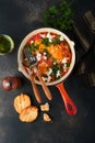 Shakshuka. Homemade fried eggs with vegetables in iron frying pan on old dark slate, stone or concrete background. Traditional cui