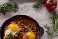 Shakshuka is a tasty dish of eggs, fried in a sauce of tomatoes, hot pepper, onion and seasonings on a black cast-iron pan. Royalty Free Stock Photo