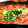 Shakshuka. Traditional jewish food and middle eastern cuisine recipe. Fried eggs, tomatoes, bell pepper and parsley in a Royalty Free Stock Photo