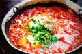 Shakshuka. Traditional jewish food and middle eastern cuisine recipe. Fried eggs, tomatoes, bell pepper and parsley in a Royalty Free Stock Photo