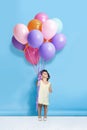 Shall we dance Mr. Balloon. a cute little girl holding a bunch of balloons against a blue background. Royalty Free Stock Photo
