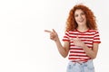 Shall we. Enthusiastic attractive redhead curly woman look curious pointing left index finger smiling happy excited