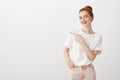 Shall we go already. Portrait of charming european redhead female in trendy oufit gazing straight and pointing left with