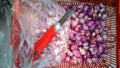 shallots in a container are in the process of peeling the skin using a rusty cutting knife Royalty Free Stock Photo