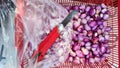 shallots in a container are in the process of peeling the skin using a rusty cutting knife Royalty Free Stock Photo