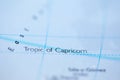 Shallow depth of field focus on geographical map location of Tropic of Capricorn line on atlas