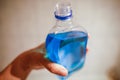 Shallow depth of field image selective focus with the hand of a man holding a plastic bottle of spirt - Romanian medical alcohol