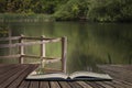 Shallow depth of field landscape image of vibrant peaceful Summer lake in English countryside concept coming out of pages in open