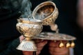 Details with the hand of a orthodox Christian nun holding a smoking metallic censer